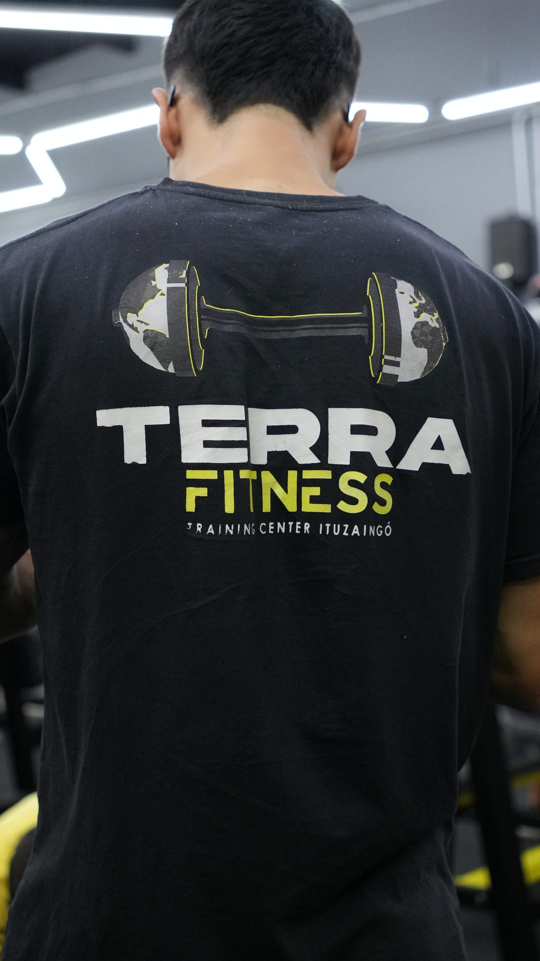 Remera de Terra Fitness junto a una mancuerna